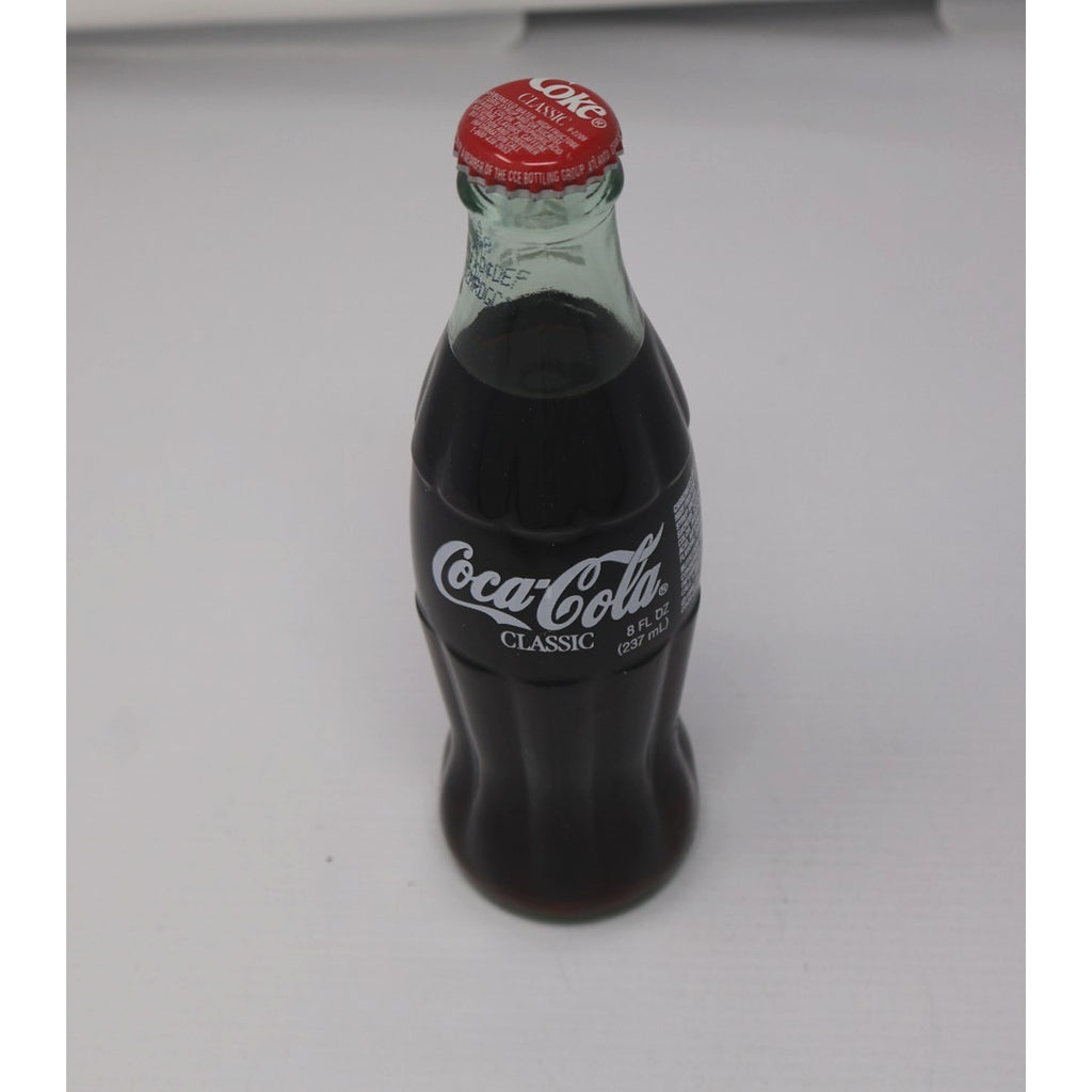 Top-down angled view of commemorative Coca-Cola bottle and collector packaging