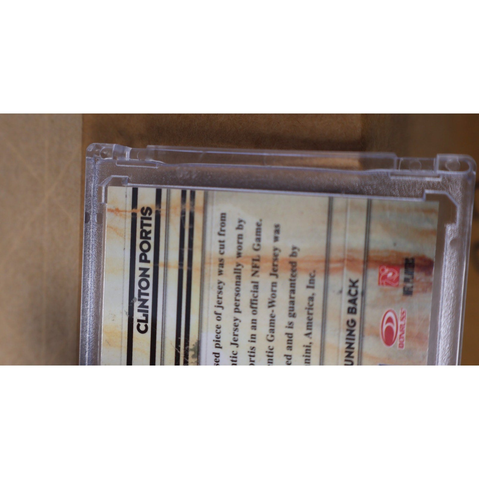 Bottom edge view of Clinton Portis Panini Absolute football memorabilia card in protective case