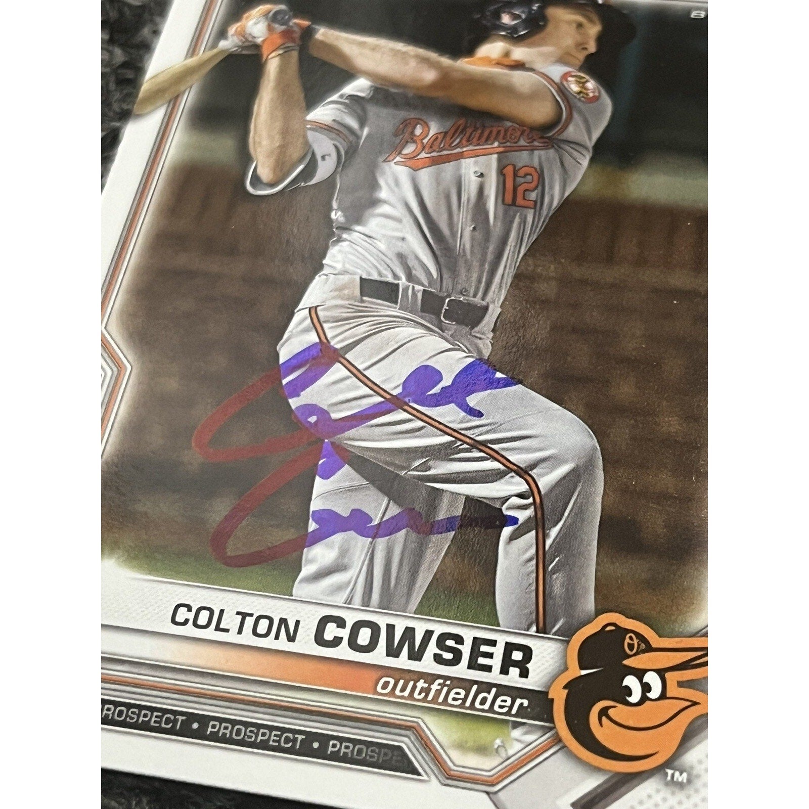 Close-up angled view of Colton Cowser autograph on 1st Bowman rookie card
