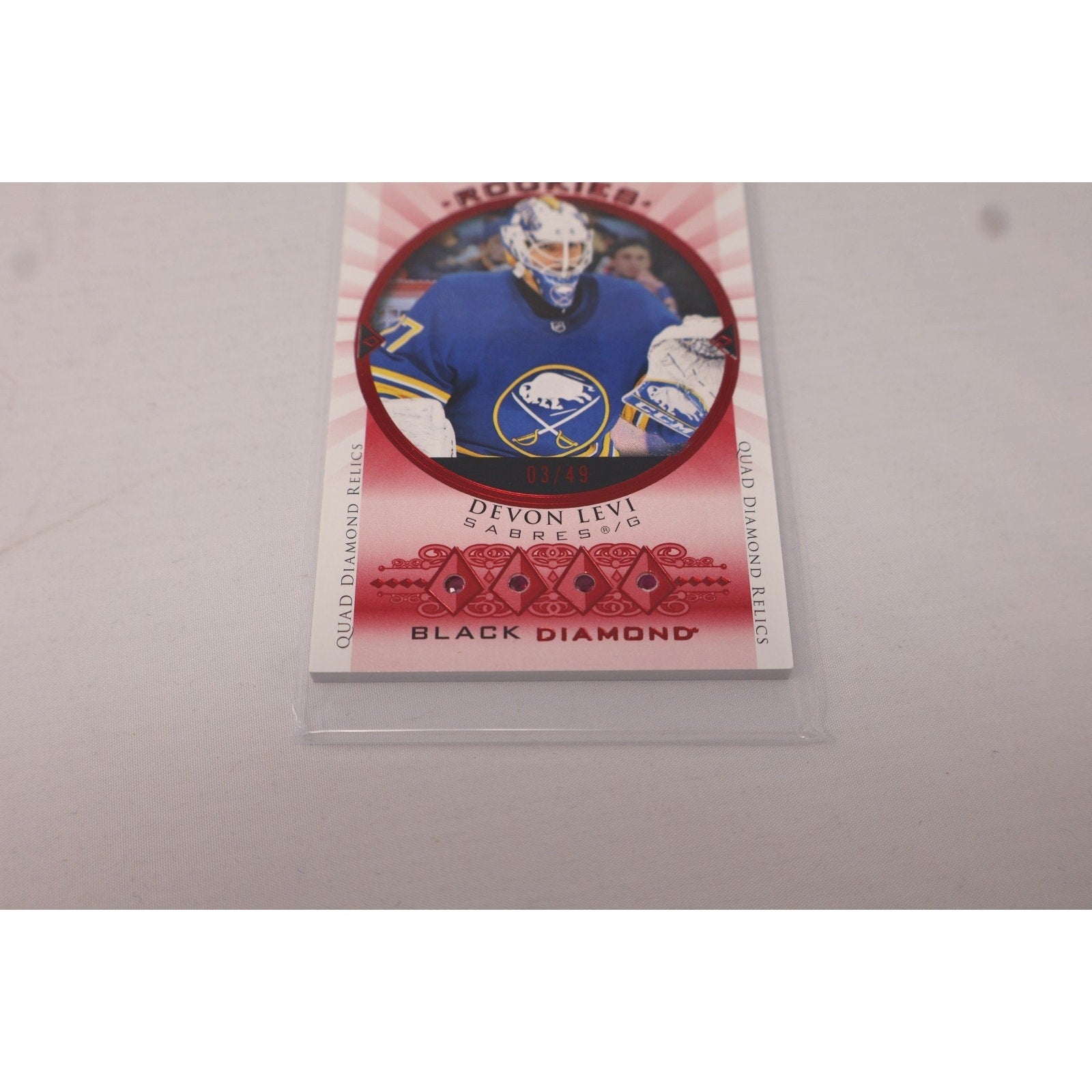 Close-up of Devon Levi Buffalo Sabres Rookie Quad Gems Relics Ruby insert card from Upper Deck Black Diamond