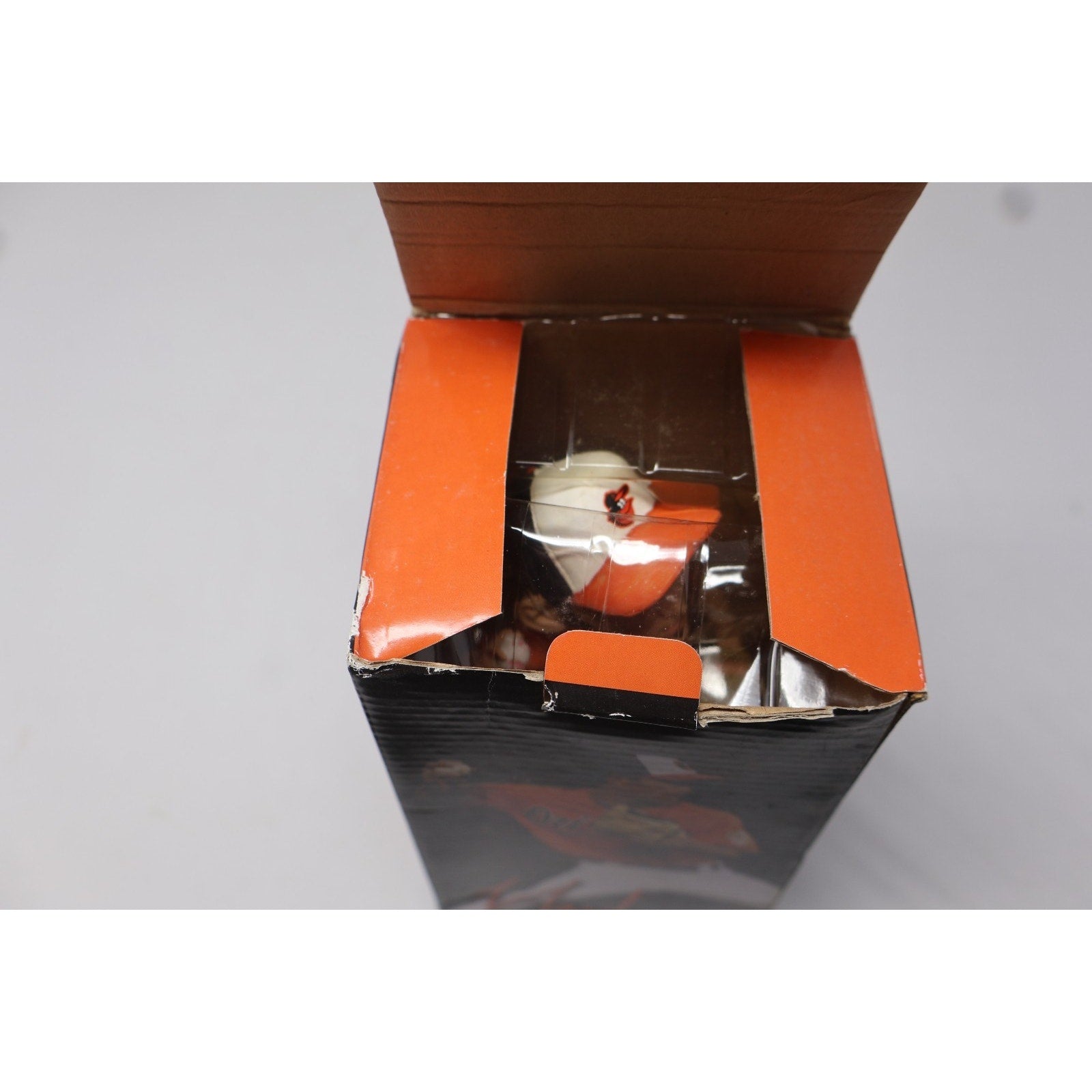 Open box with orange interior showing a product inside on a gray background