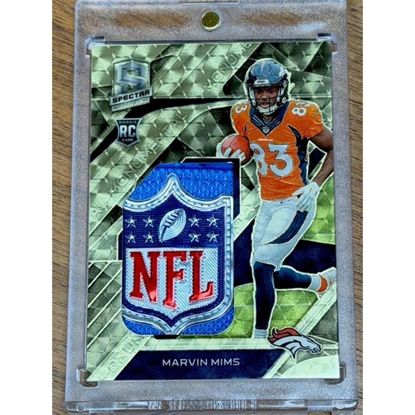 Front view of a 2023 Panini Spectra Marvin Mims Jr. Gold Vinyl NFL Shield rookie patch card numbered 1/1 featuring the Denver Broncos rookie receiver