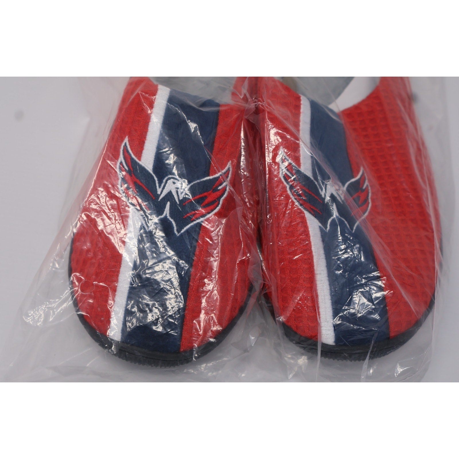 Front angled view of Capitals themed slippers in unopened packaging