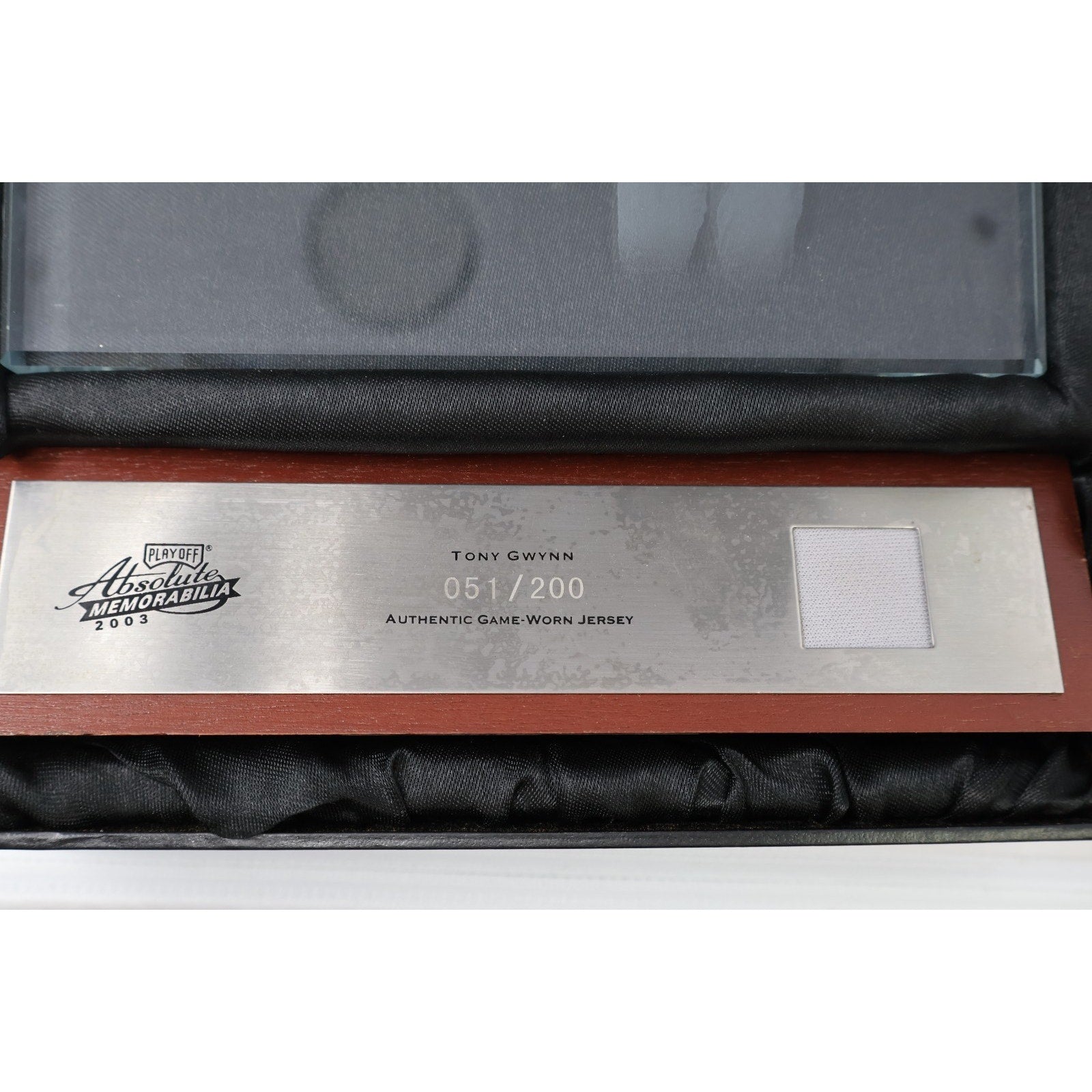Close-up view of the game-used jersey relic swatch and engraved nameplate on the Tony Gwynn glass plaque display