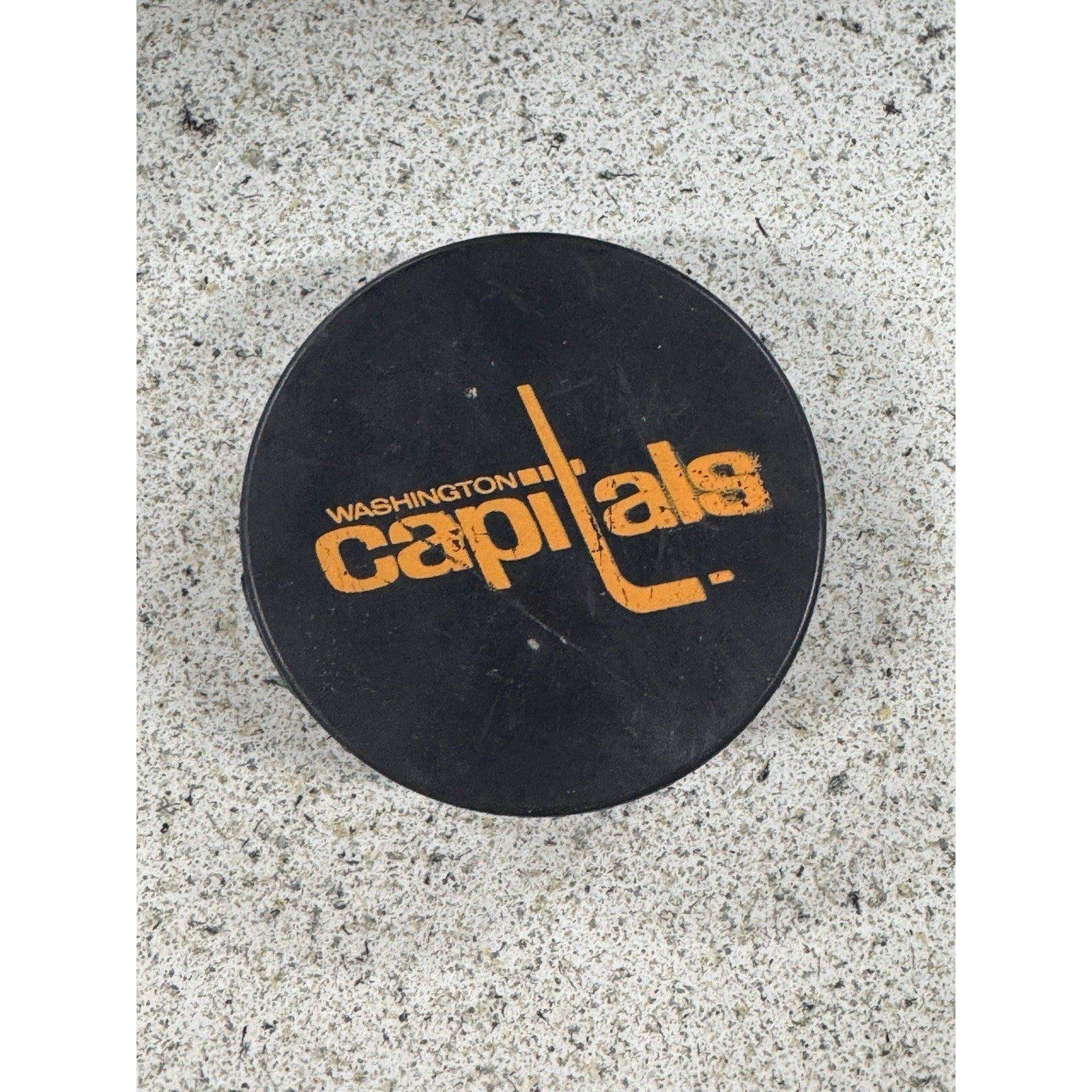 Vintage Washington Capitals hockey puck with retro orange logo on black rubber