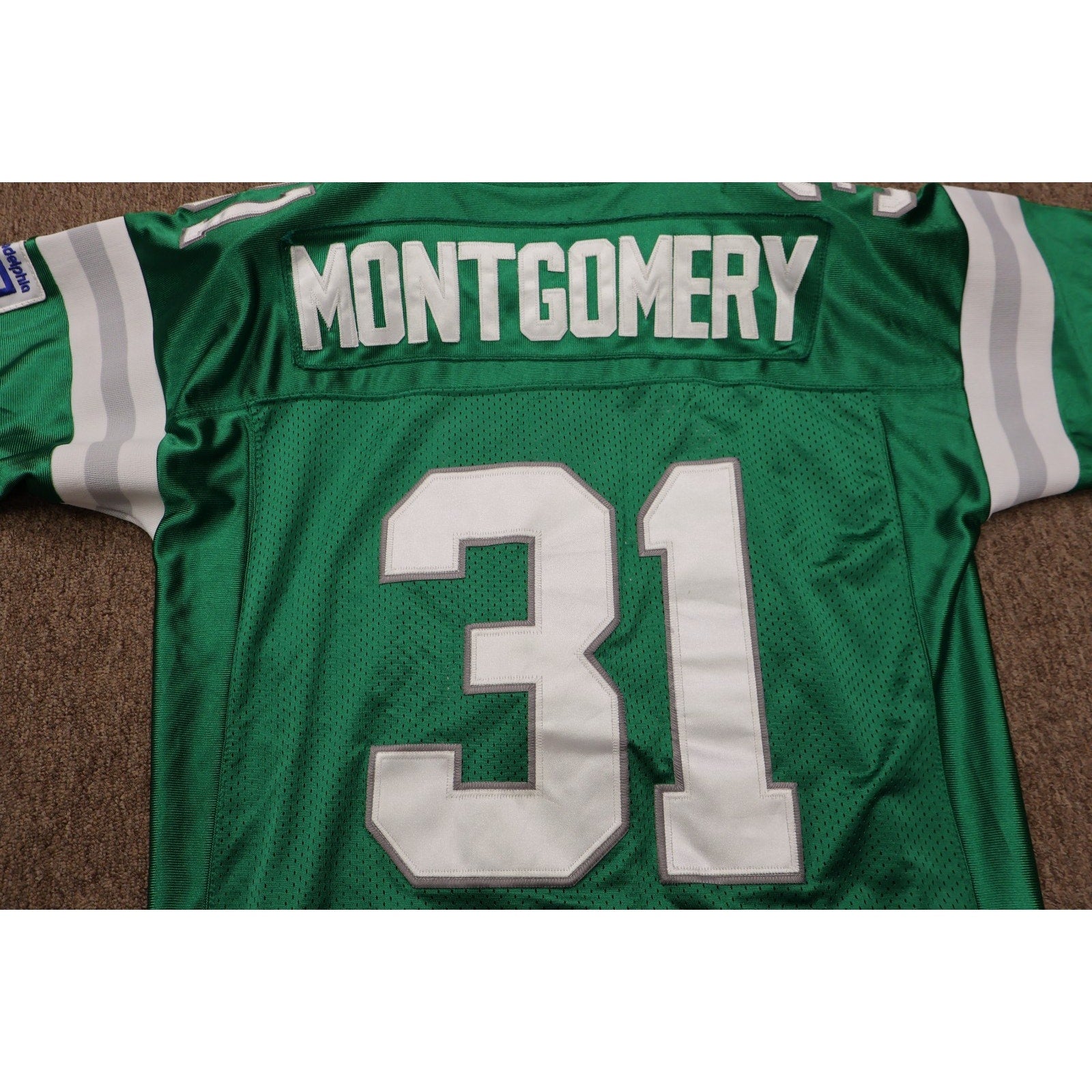 Green sports jersey with 'Montgomery' and number '31' on a brown surface